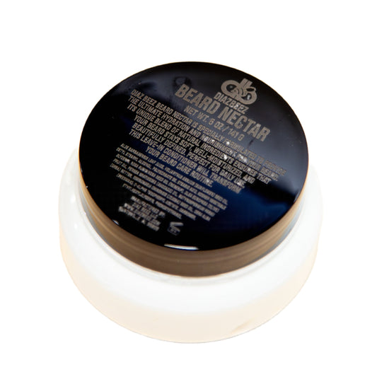 A round container featuring a dark lid labeled "Beard Nectar - Conditioning Cream" and "Diaz Beez" sits on a light surface. The text on the lid contains product information in small print.